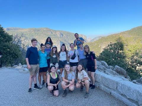       A group of people posing in front of a mountainous landscape.
  