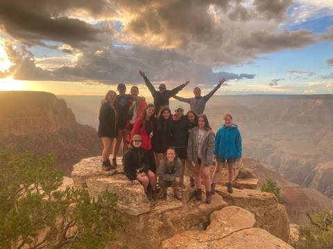       Group of people posing on a cliff with a canyon view.
  