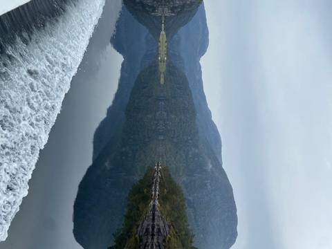 A fjord with misty mountains reflected in water.