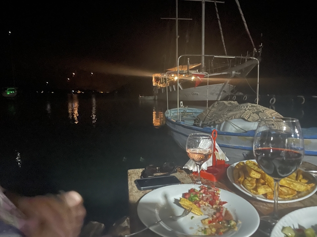 Nighttime dining scene on a boat with water and lights in the background.