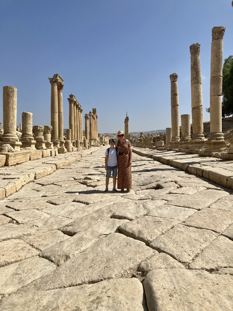 Two people standing in the ancient ruins of Jerash with columns.