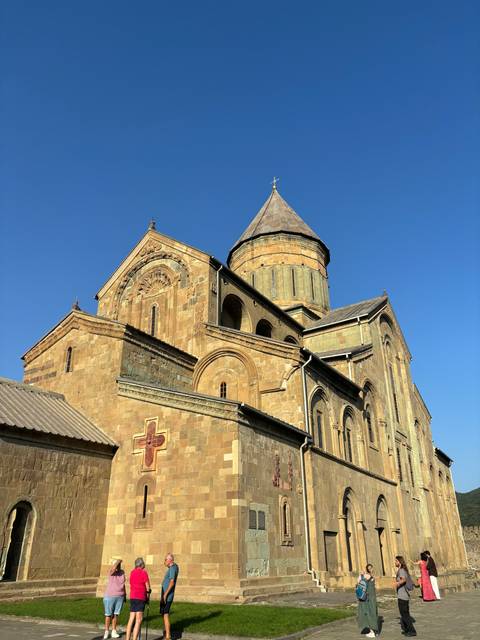 Historic stone church with tourists outside.