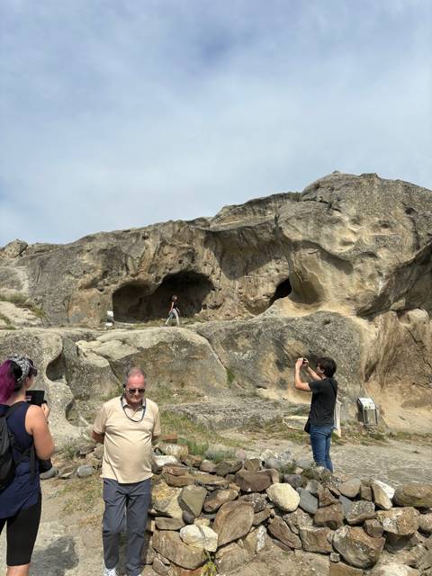 People exploring cave dwellings in a rocky landscape.
