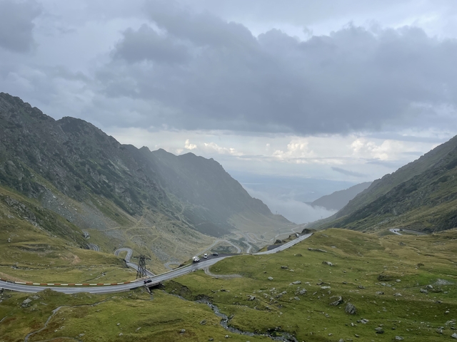Mountain pass with a winding road and cloudy sky.
