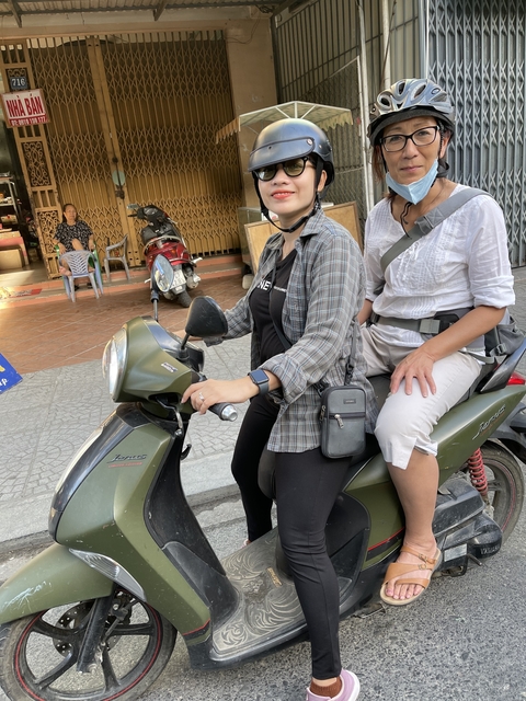 Two people on a motorbike in an urban setting.