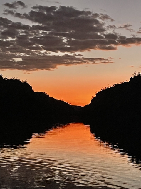 Silhouette of hilly landscape against an orange sunset.