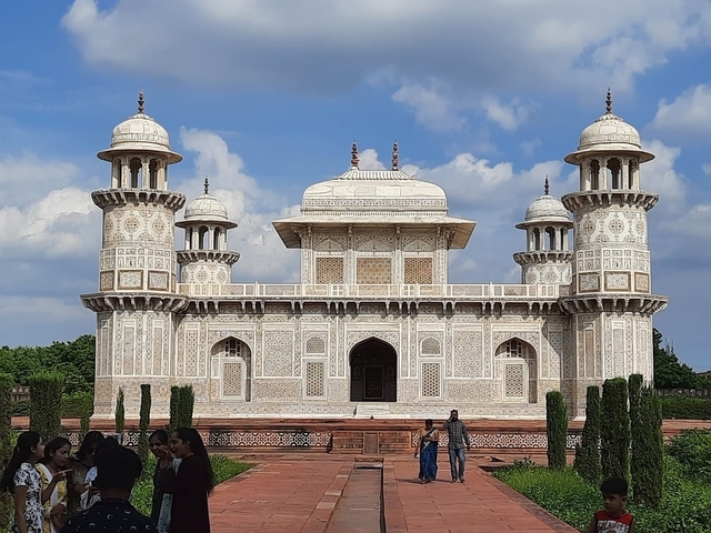       Ornate tomb with people in the foreground.
  