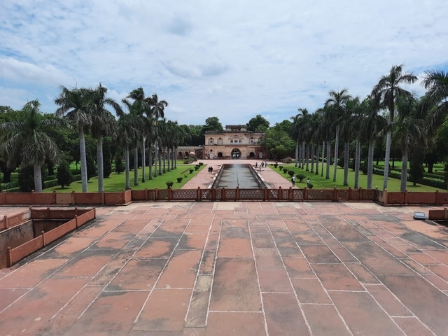       Palace garden with a water fountain and palm trees.
  