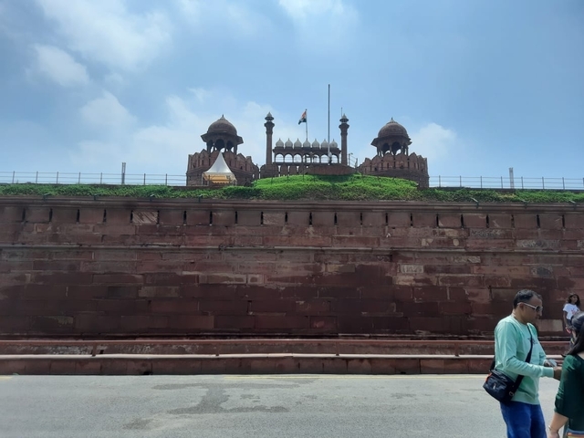       Red Fort with tourists walking in front.
  