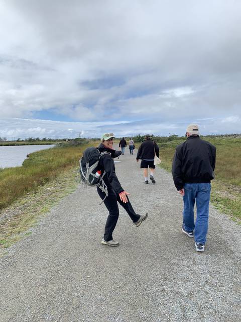 People walking on a gravel path with a cloudy sky.