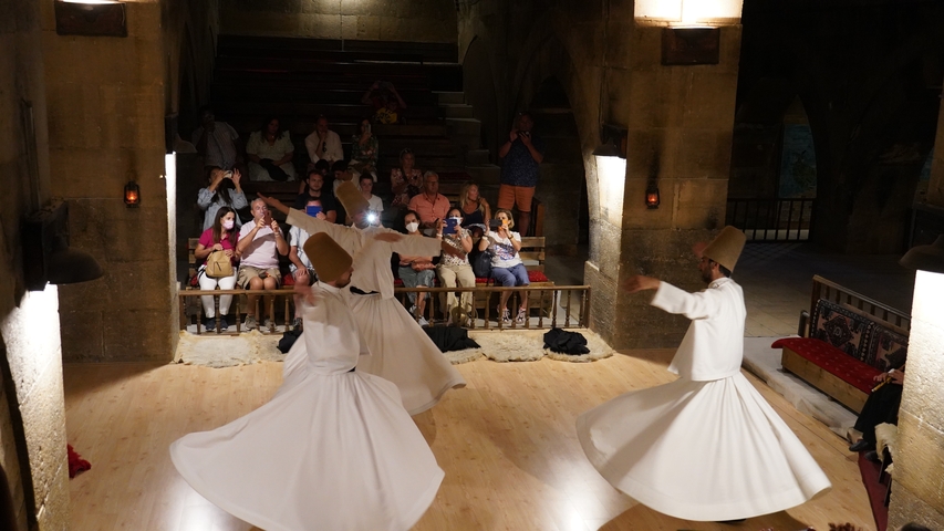 Dervishes whirling in a cultural performance with an audience.