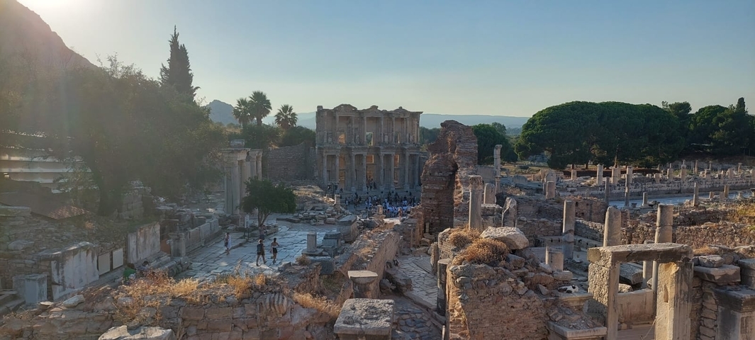 Ancient ruins with trees and people in the background.