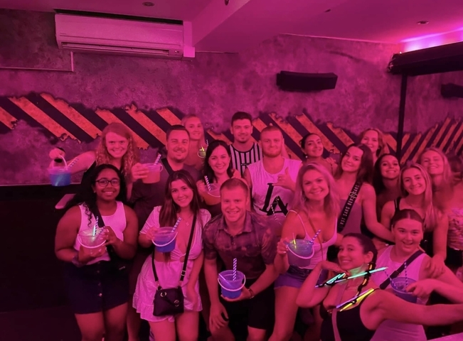 Group of people holding drinks in a dimly lit venue.