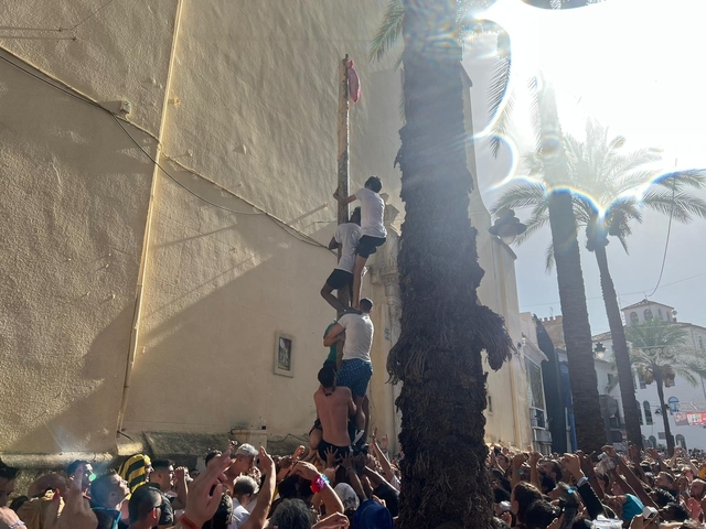 People stacking up to climb a greased pole.