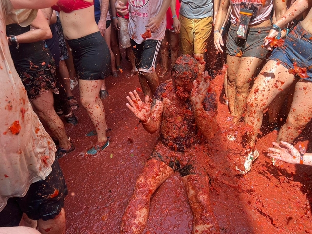 Group of people covered in smashed tomatoes at a festival.