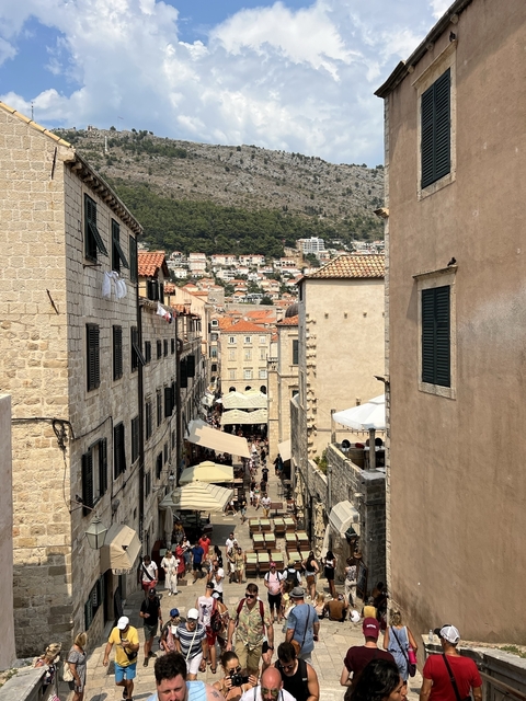 View of a narrow street in a historic town with red rooftops.