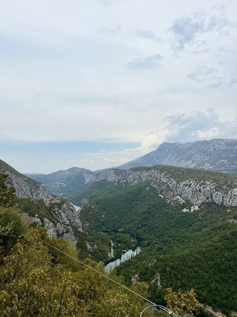 Mountainous landscape with greenery and cloudy sky.