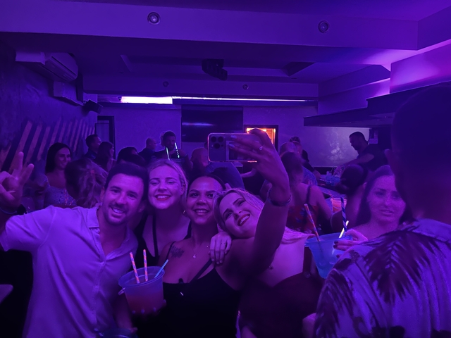 Group of friends taking a selfie in a dimly lit club.