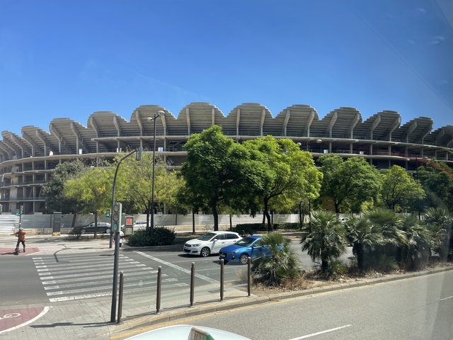 Large stadium surrounded by lush greenery in a city.