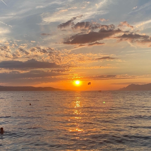 Beautiful ocean sunset with a parasailer in the distance.
