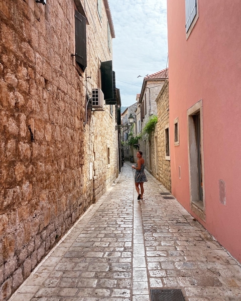 Woman walking through a narrow cobblestone street.