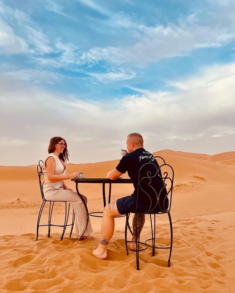 Couple enjoying coffee at a table in the desert.