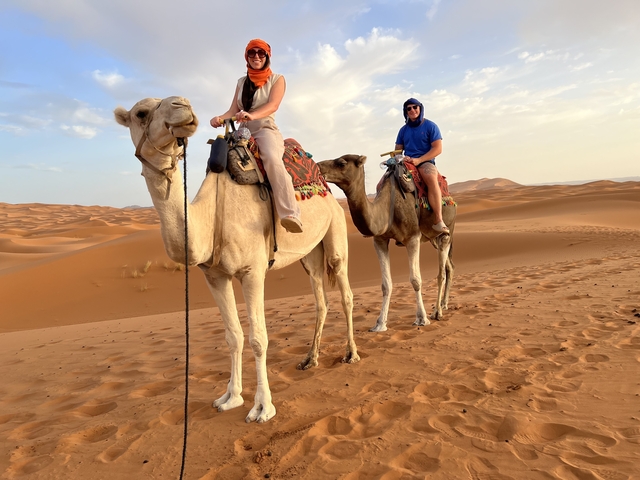 People riding camels across desert dunes.