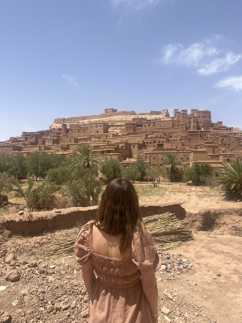 Person viewing a historic Moroccan kasbah from a distance.