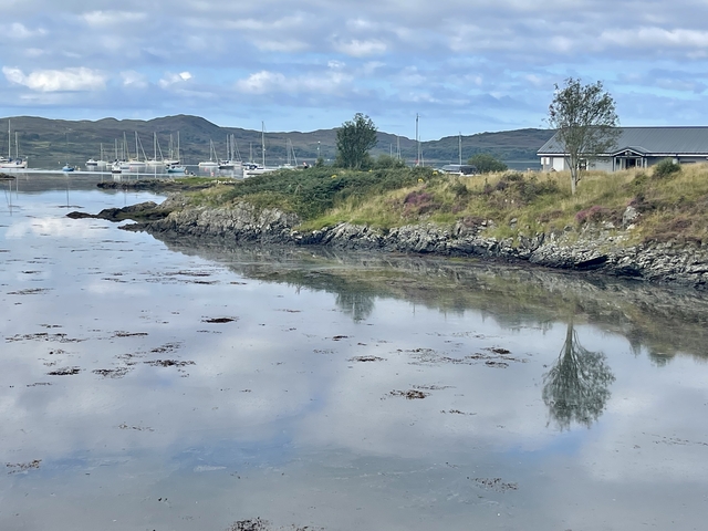Waterfront scene with boats and hills in the background.