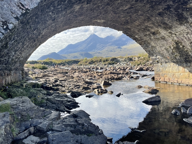 Stunning mountain view framed under a stone arch bridge.