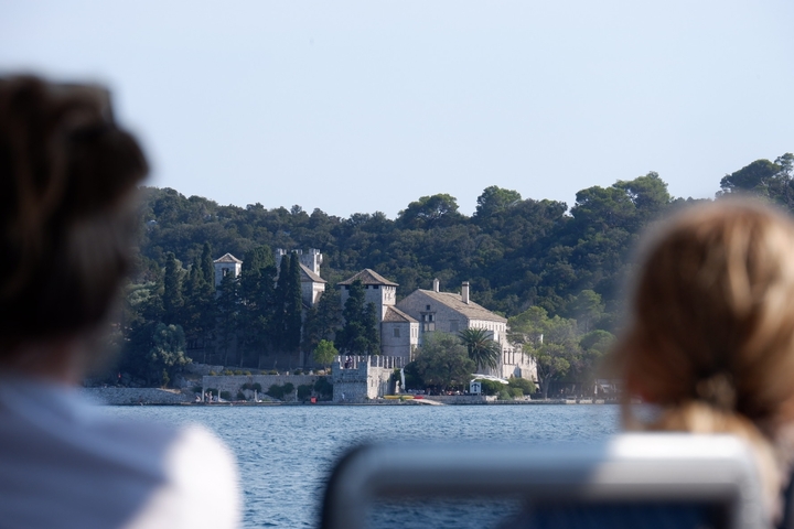 View from a boat showing a historic mansion and two people.