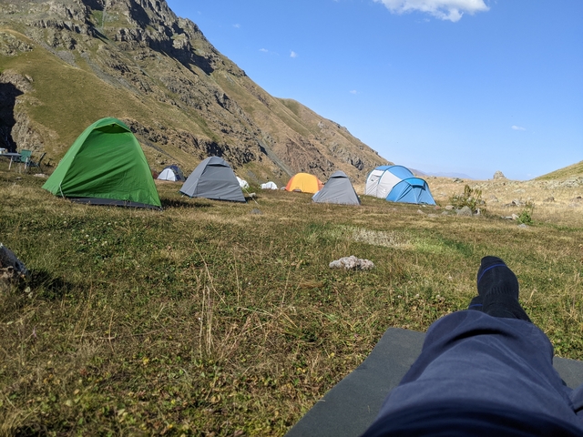 A campsite with several colorful tents set up on a grassy plain.
