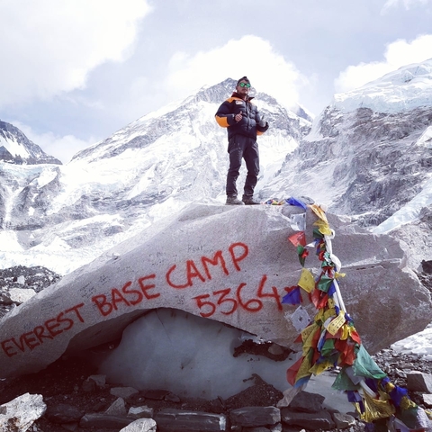       Traveler at Everest Base Camp with snowy peaks.
  