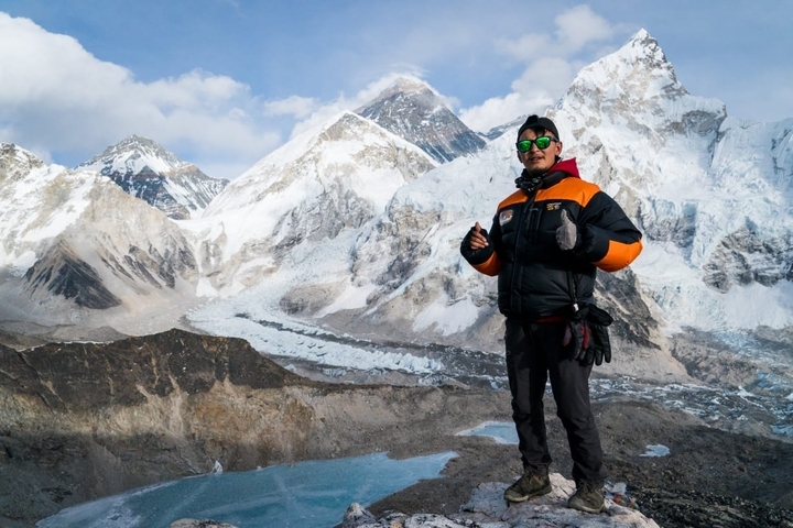       Person posing with snowy peaks in the background.
  