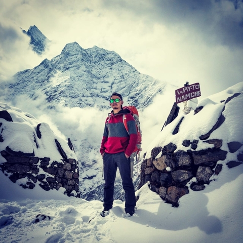       Person on a snowy path with mountain backdrop.
  