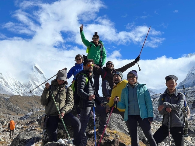       Group of hikers posing with trekking gear against mountains.
  