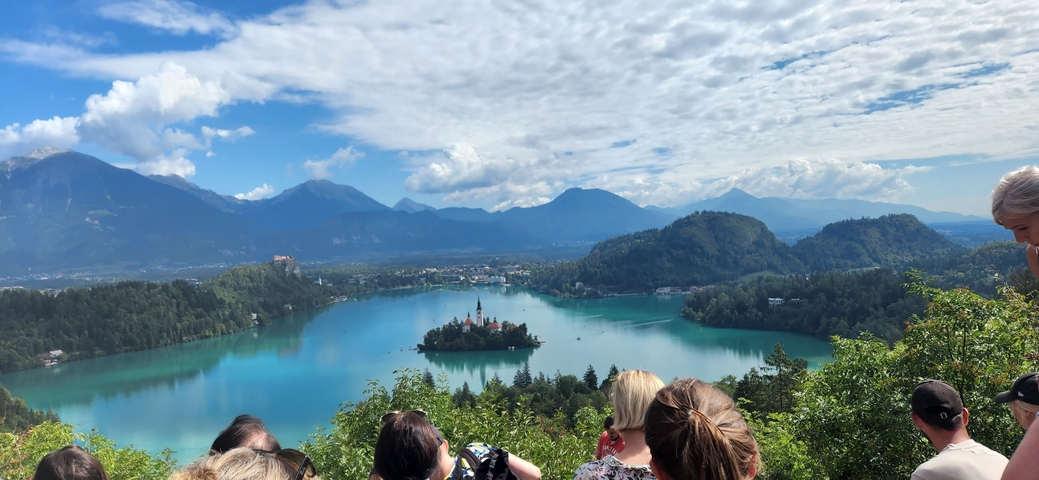       Group of tourists viewing a lake with a church on an island.
  