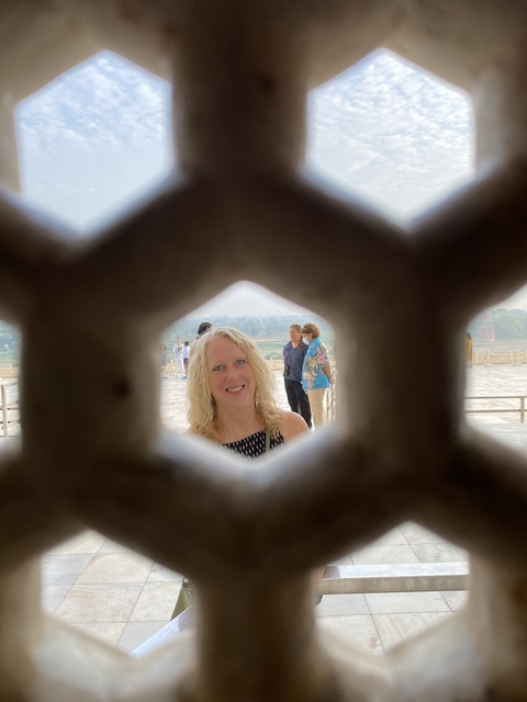       Portrait of a woman with a view through a carved screen.
  