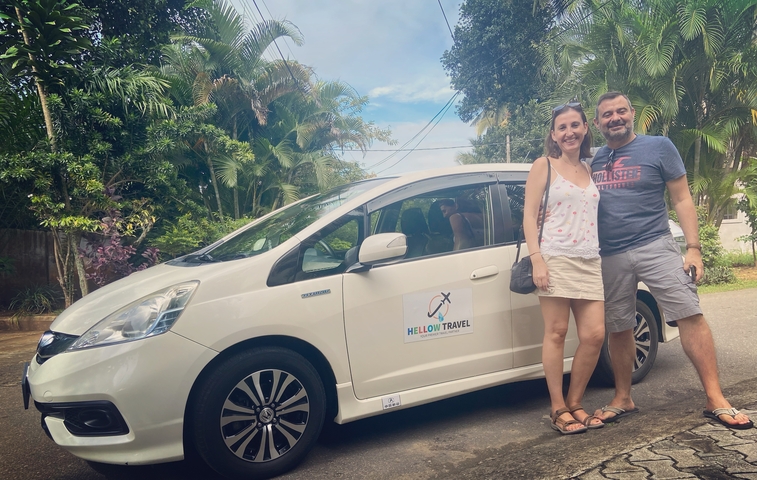       Couple standing beside a car with travel company advertisement.
  