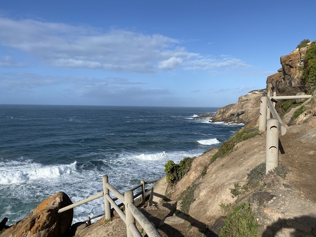 Coastal walkway with ocean view and clear skies.