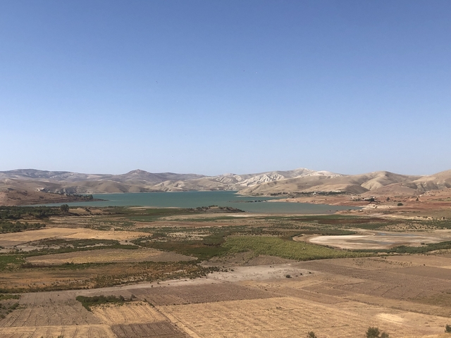       Scenic view of a lake surrounded by fields and mountains.
  