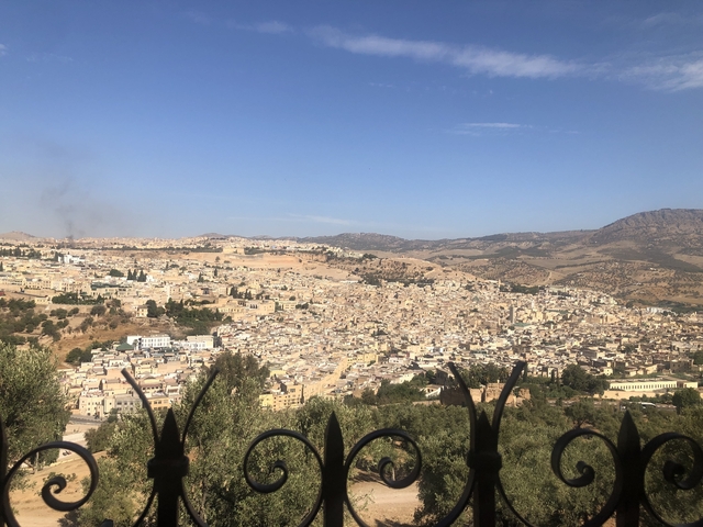       Panoramic view of a city over rolling hills.
  