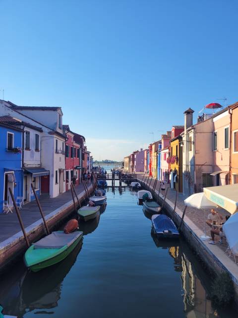 Colorful buildings lining a canal with boats in a sunny setting.