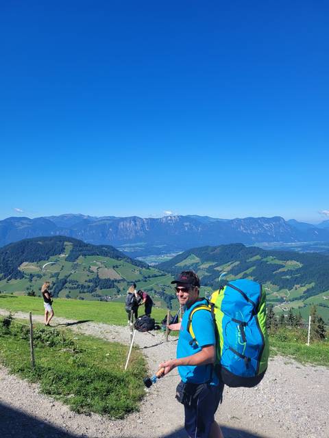 Hikers carrying backpacks on a trail with mountainous landscape.