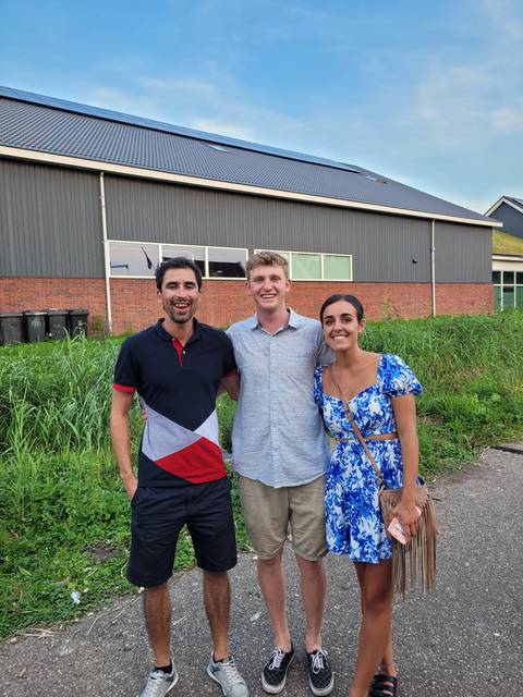 Three people posing in front of a building.