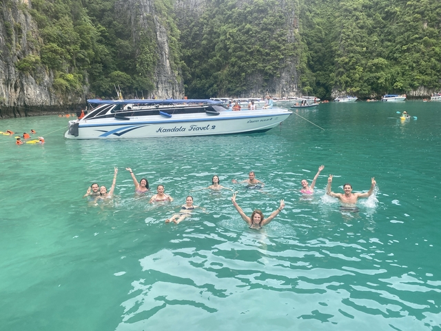Group of people swimming in a turquoise lagoon with a speedboat.
