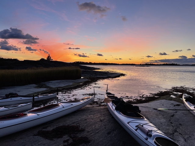 Kayaks by a serene waterfront at sunset.