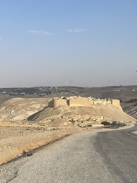       Ancient ruins with wind turbines in the background.
  