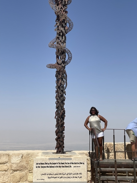       Sculpture with a woman standing beside it in an open space.
  