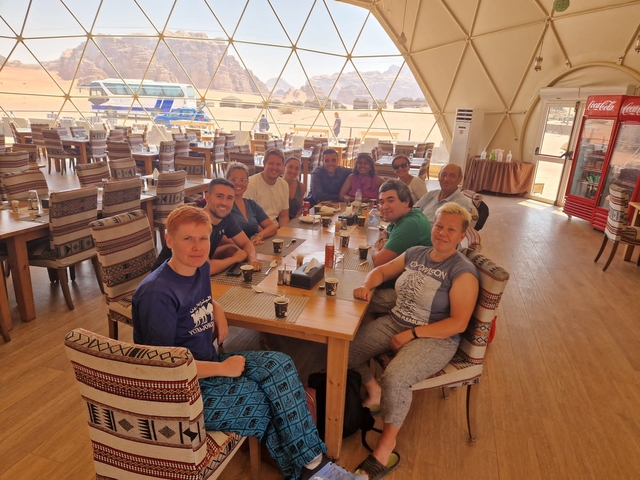 Group of people seated at a dining table inside a dome tent.